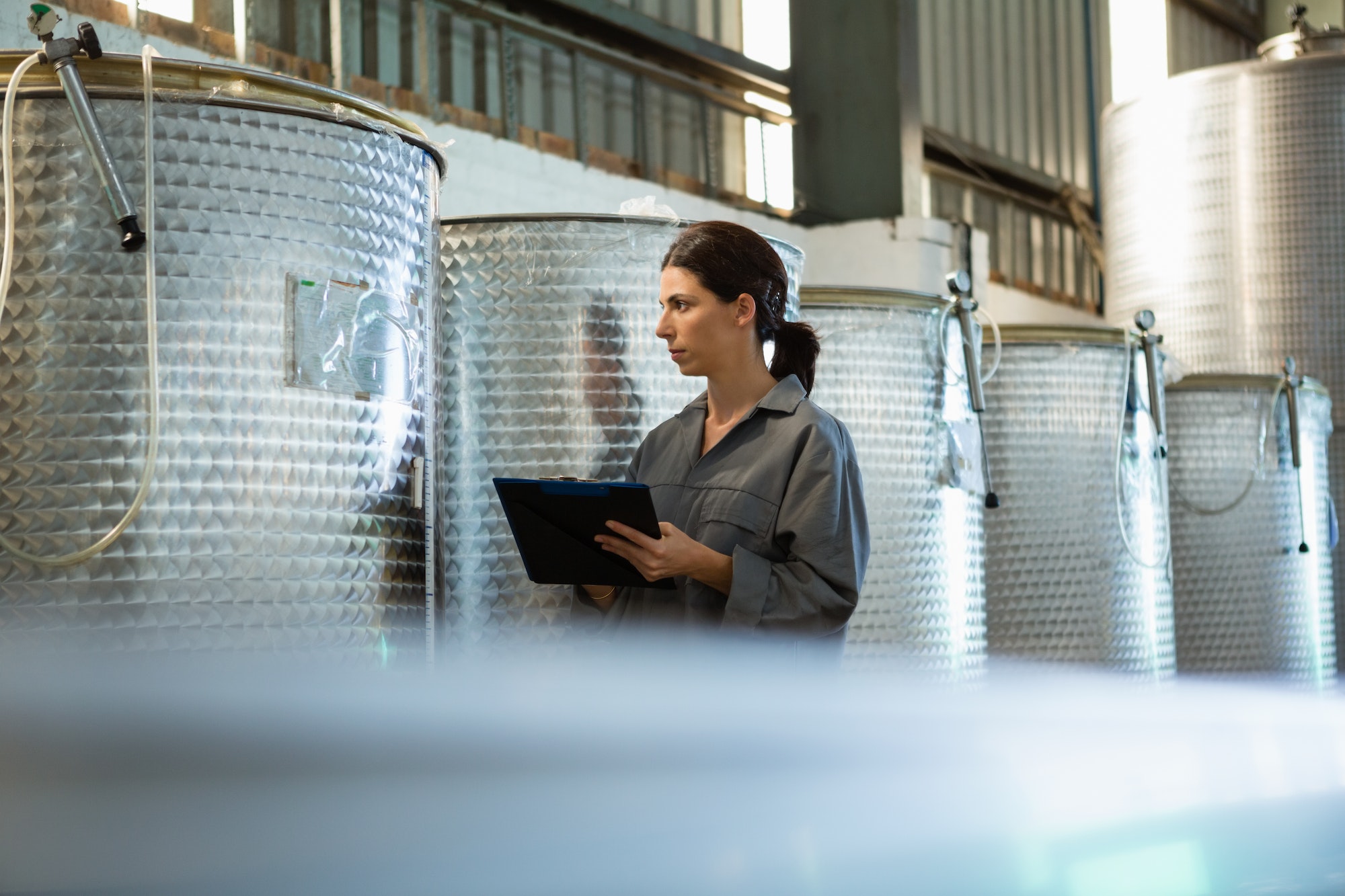 Female worker writing on clipboard in olive factory